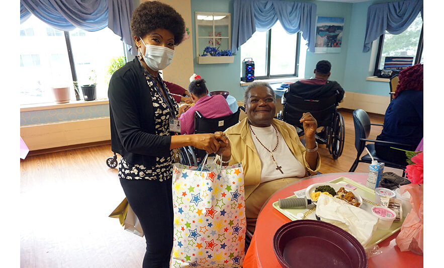 Extended Care Adopt-a-Resident Day 5-11-2022 Veronica Onwunaka giving gift bag to woman for web