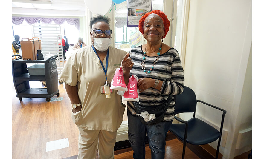 Extended Care Adopt-a-Resident Day 5-11-2022 Woman showing off sneakers with employee for web